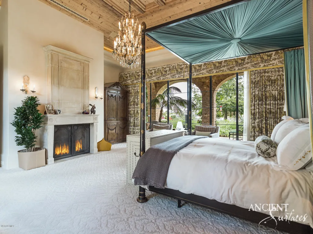 Master suite with a carved antique limestone fireplace mantel and arched stone windows